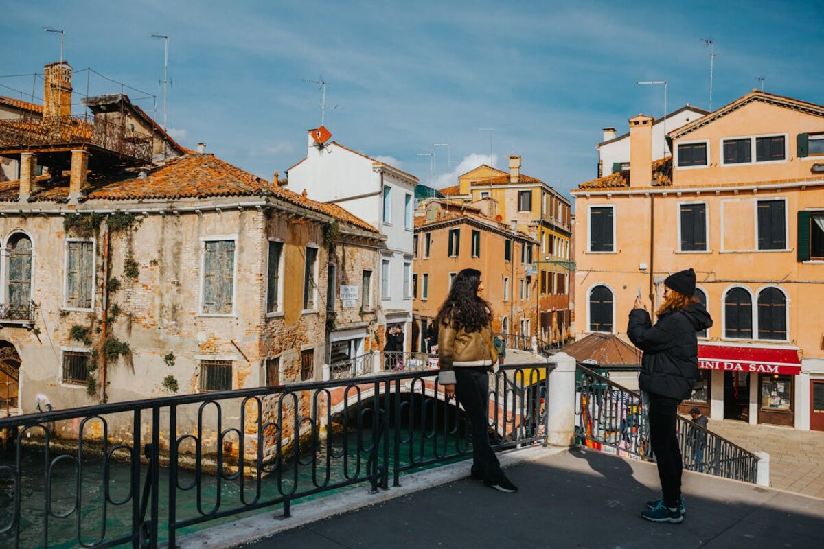 Two tourists admire the scenic architecture and waterways of Venice, Italy on a sunny day.